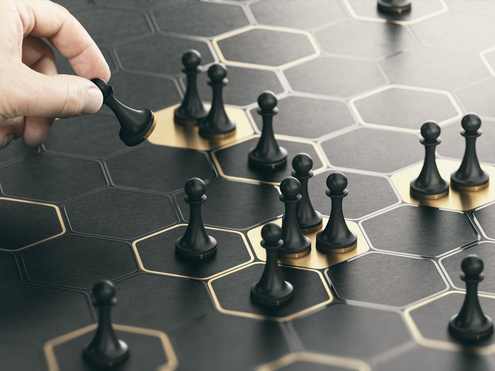 A hand placing a piece on a hexagonal gold and black board.
