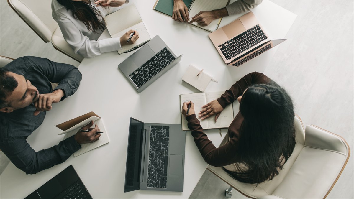 A small team working together around a table with laptops and notebooks.